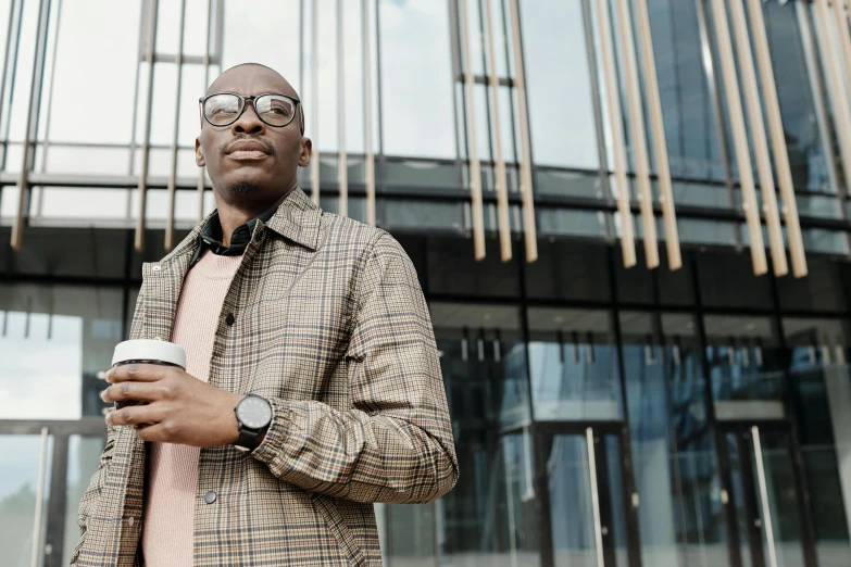 the man is wearing glasses and is drinking coffee