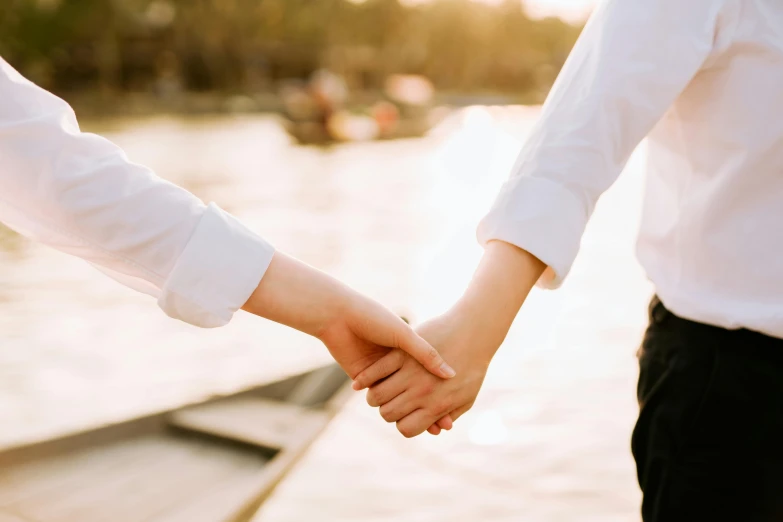 a couple hold hands while walking near the water