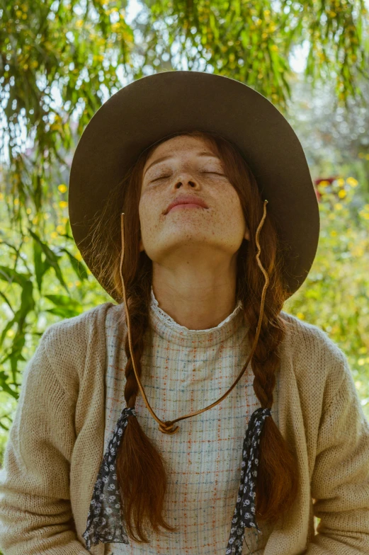 a woman wearing a brown hat and dress in the forest