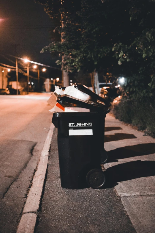 a black garbage can sitting next to a curb