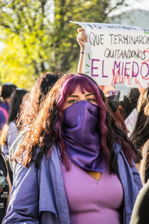 an image of a woman wearing a purple mask holding up a sign