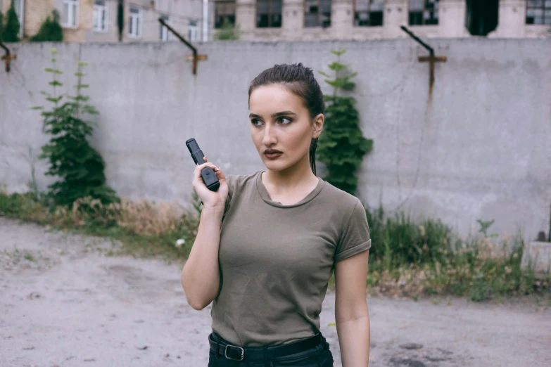 a beautiful young woman holding a cell phone while standing in front of a building