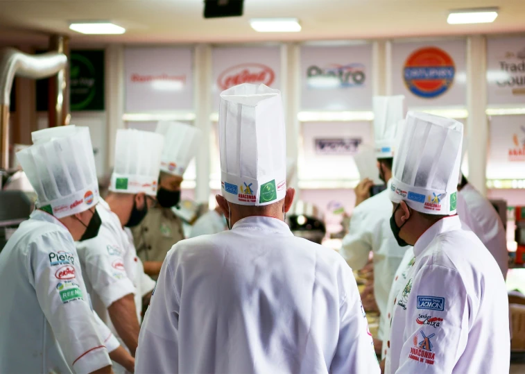 a group of chefs in white uniform are looking at the wall