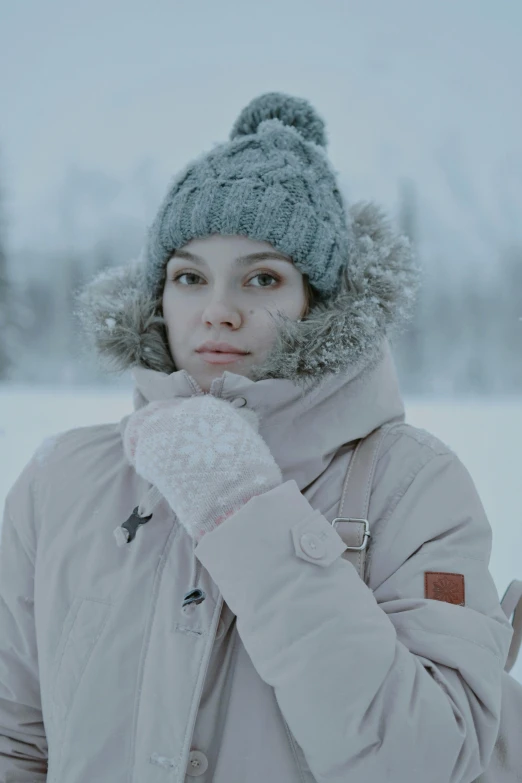 a young woman with blue eyes wearing a winter hat and gloves