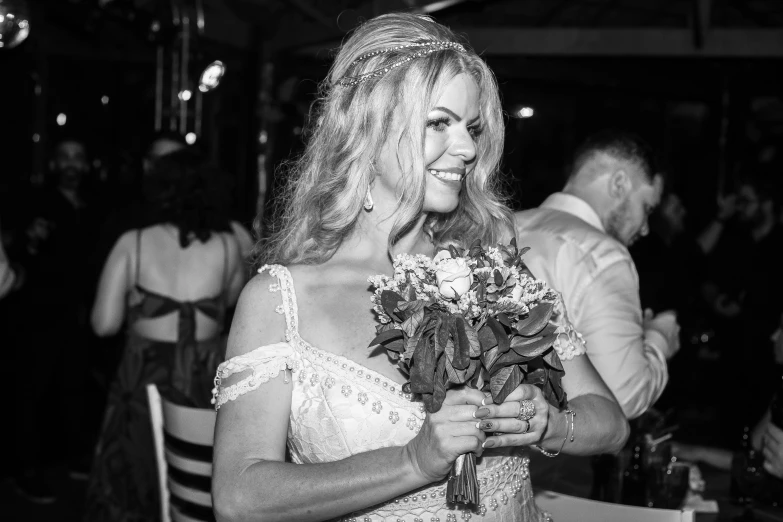 a smiling woman in a strapless dress holds a bouquet of flowers