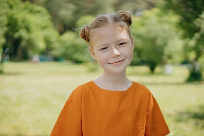 a smiling child in an orange shirt in a field