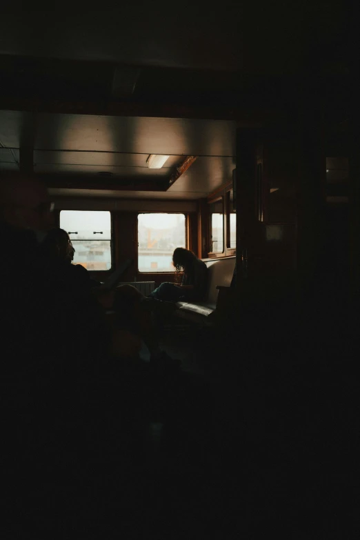 a black - and - white po of a person sitting by a window in a dimly lit room