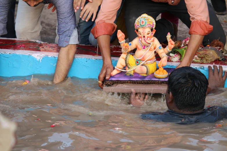 a person sits on the ground surrounded by water, as others sit down to worship him