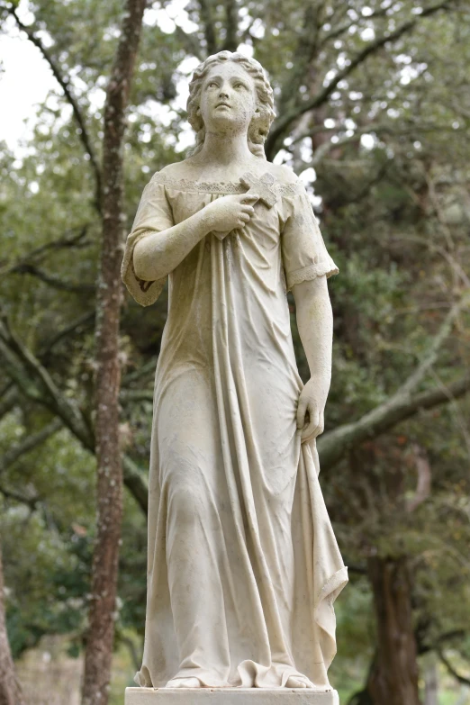 a white statue of a person holding a cross