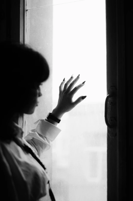 a black and white po of a woman holding her hand out a window