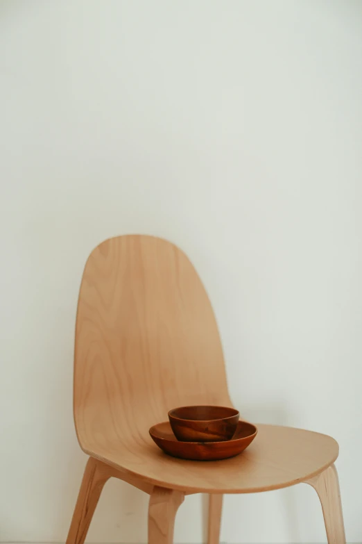 three wooden bowls sit on a small wooden chair