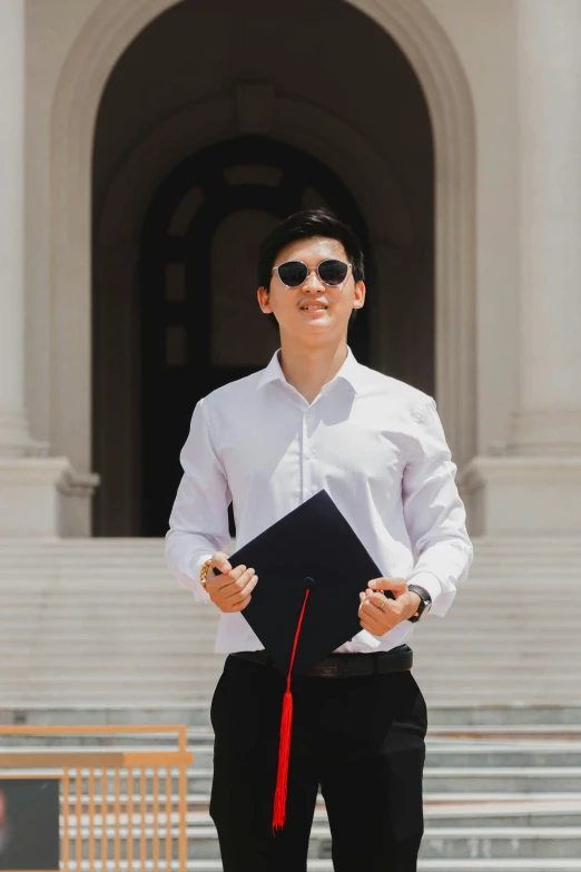 man in formal clothes holding a folder and wearing sunglasses