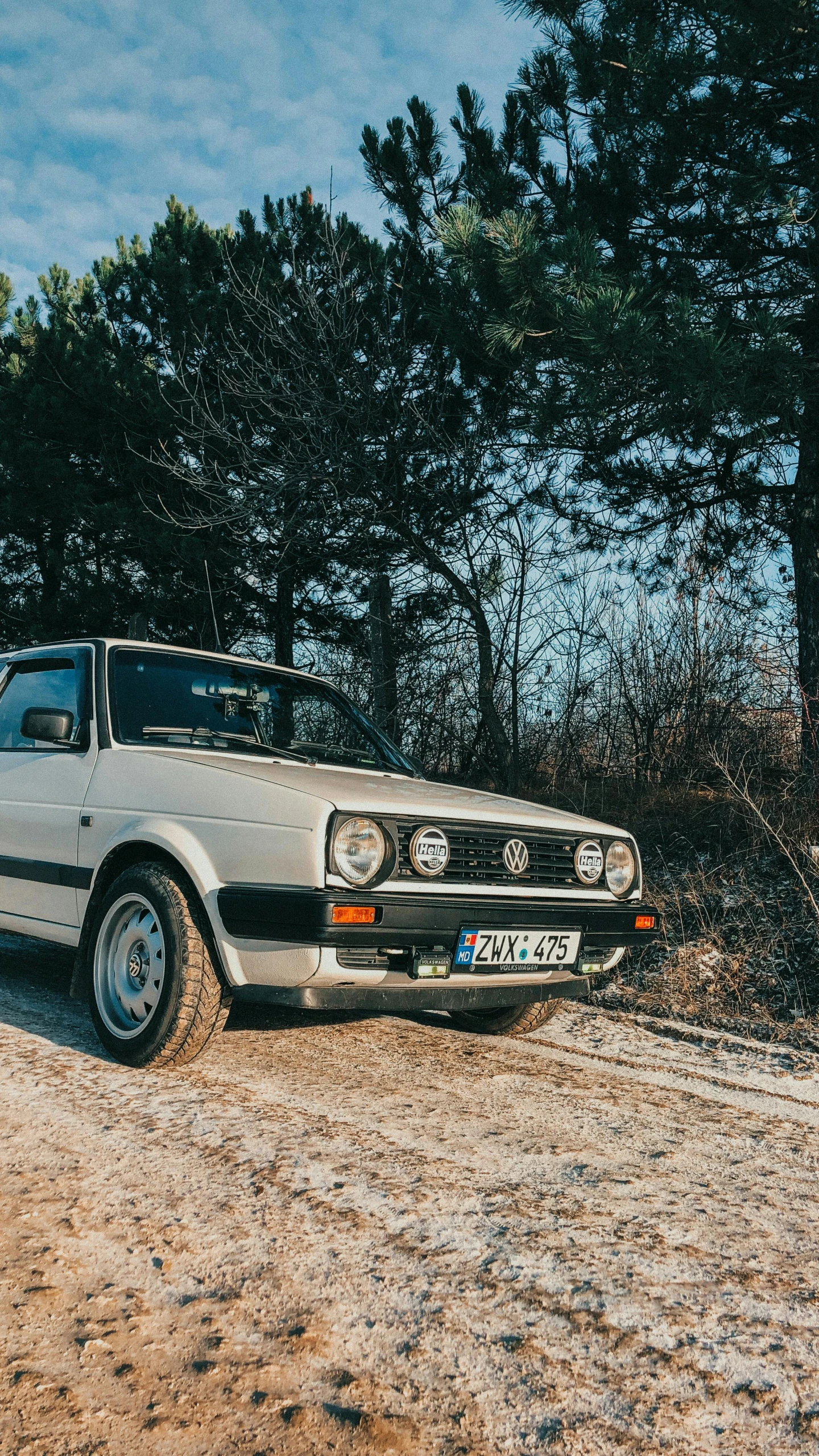 this white car is parked on a dirt road