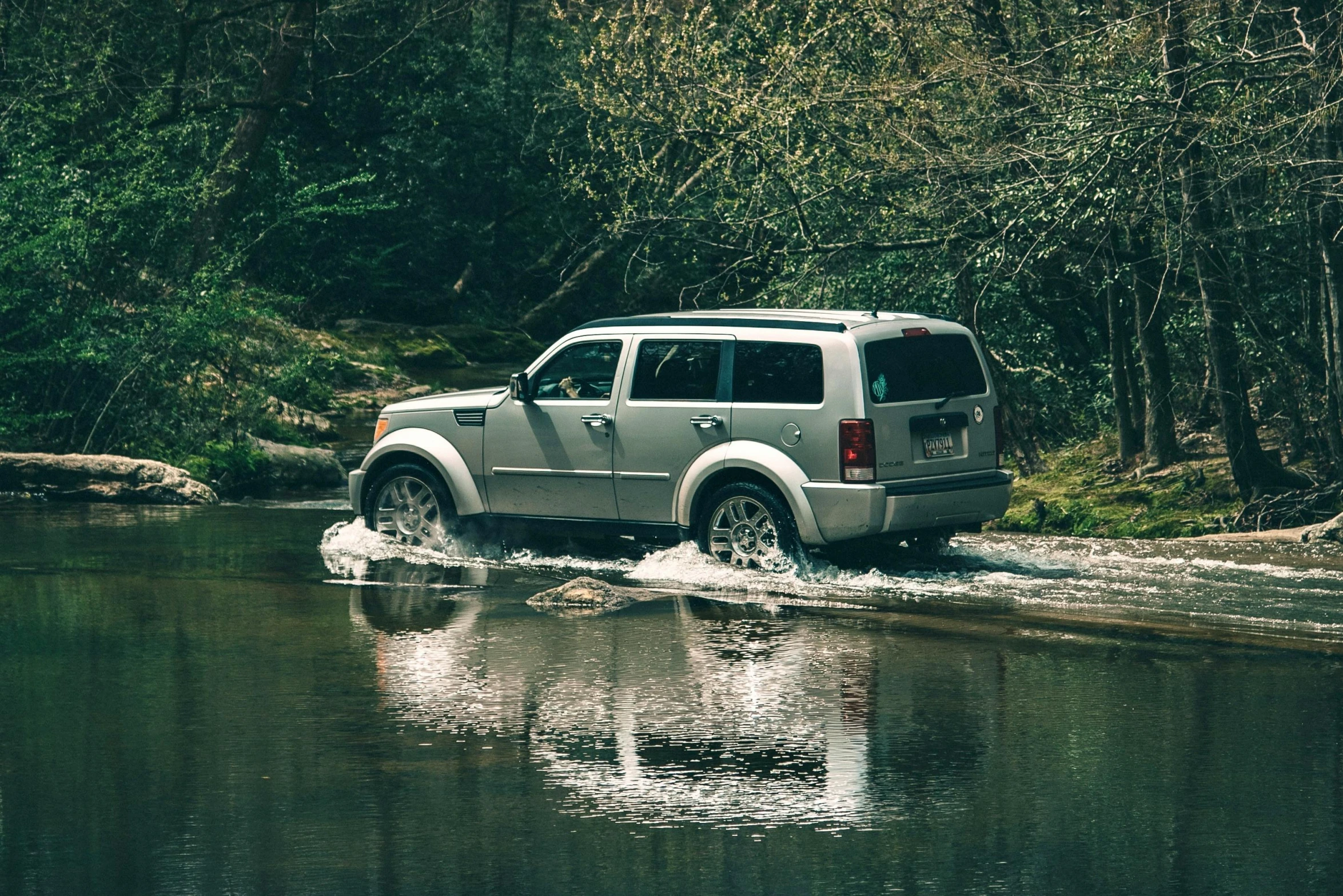 a car is driving through some water and trees