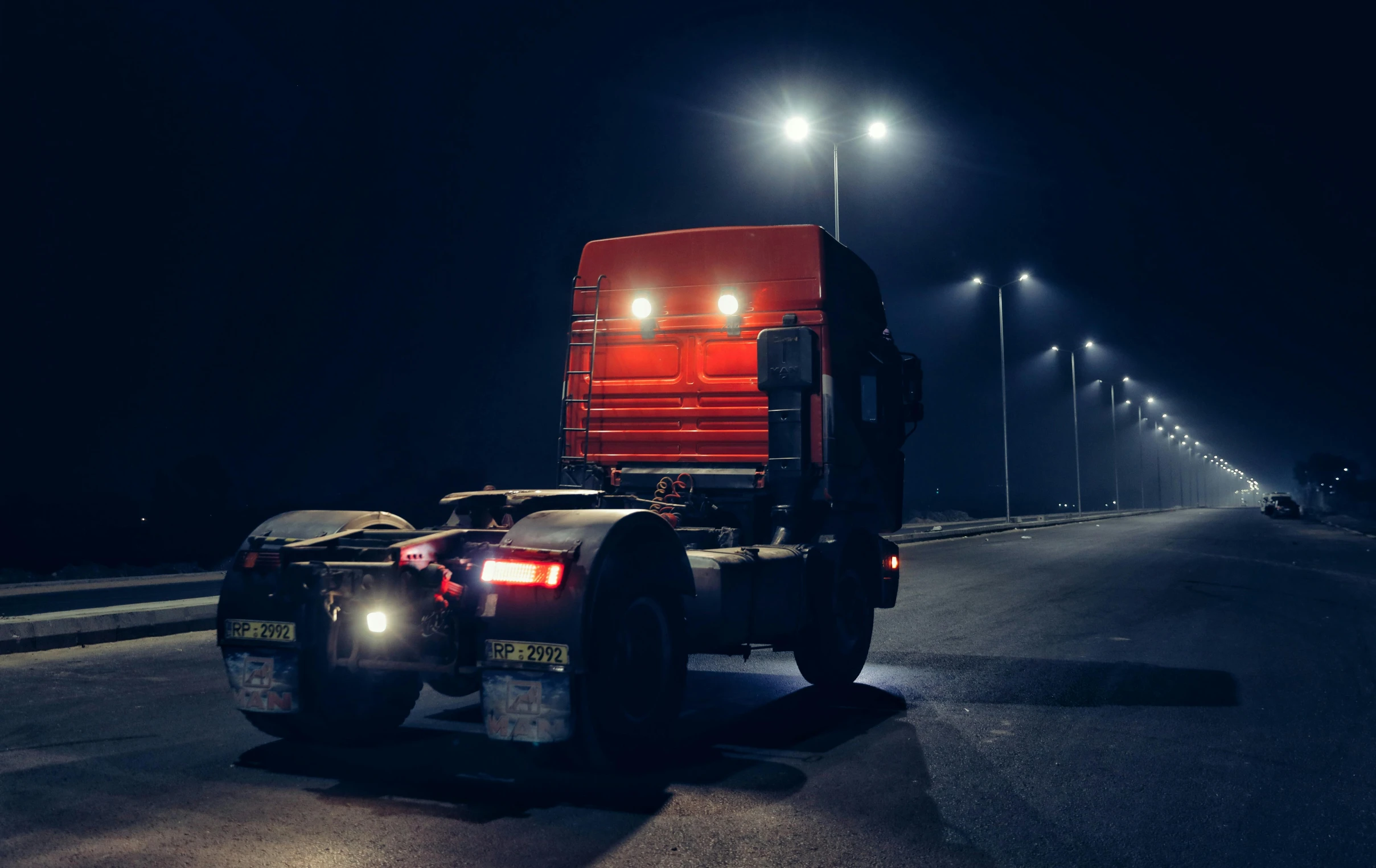 red truck with lights on driving down the highway at night