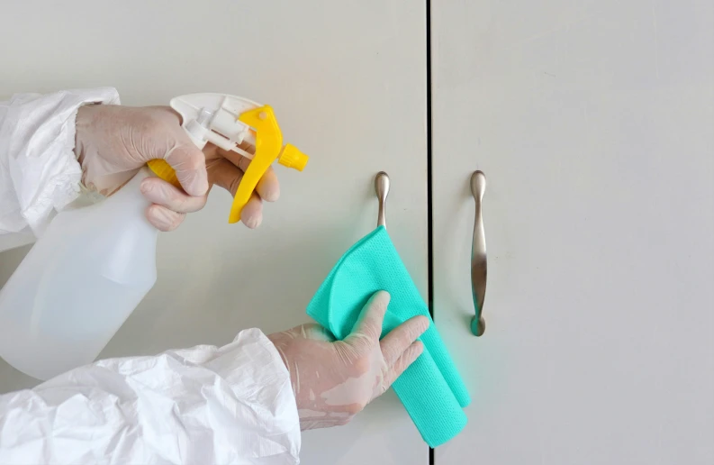 gloved hand with protective gloves holding a sponge to a door handle