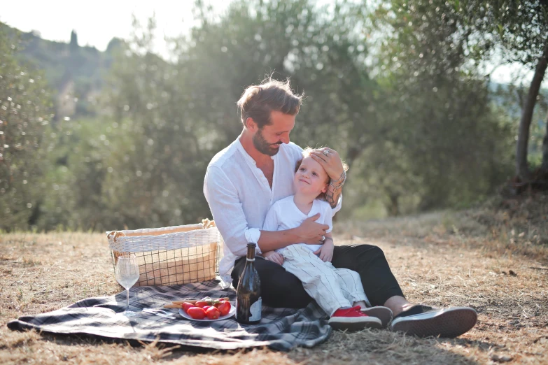 a  sitting next to a man on a blanket