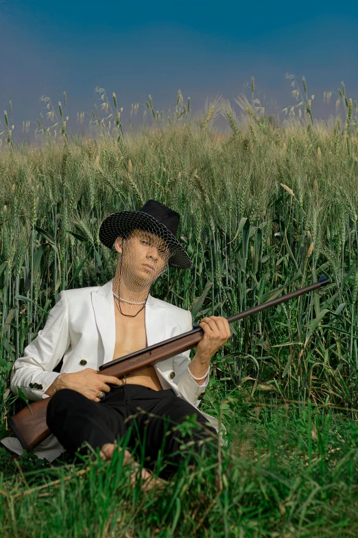 a man that is sitting in the grass holding a sgun
