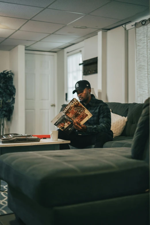 man on couch reading an interesting book in apartment