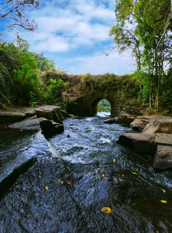 the view from a river looking down at rocks, and an arched bridge