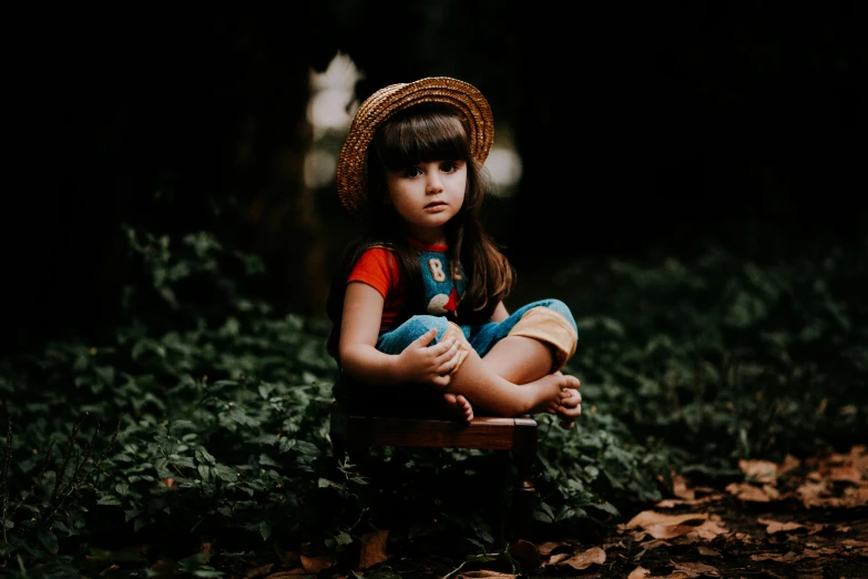 a young child sits on a wooden bench in a forest