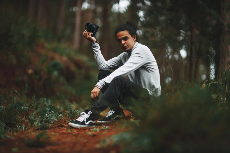 a man sits in the woods while holding soing in his hand