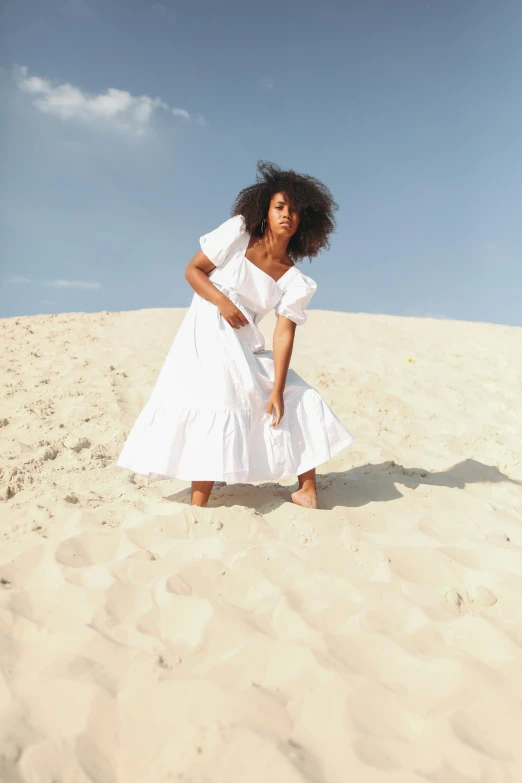 a woman in white dress standing on a sandy area