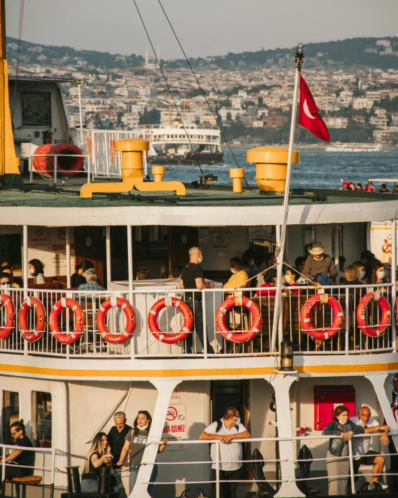 the large ferry is full of people and has a red round sign