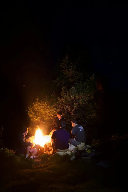 three people are around a fire in the dark