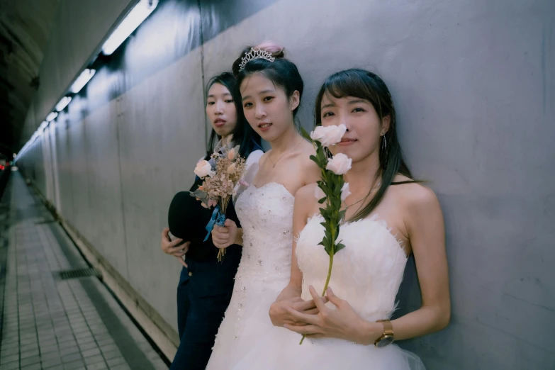 three brides pose in a subway station