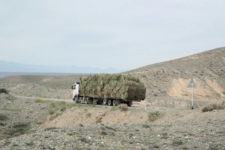 a truck carrying hay is coming down a hill