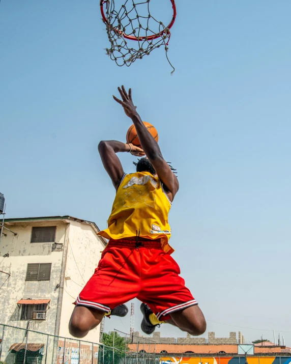 a person dunking at a basketball net on an outdoor court