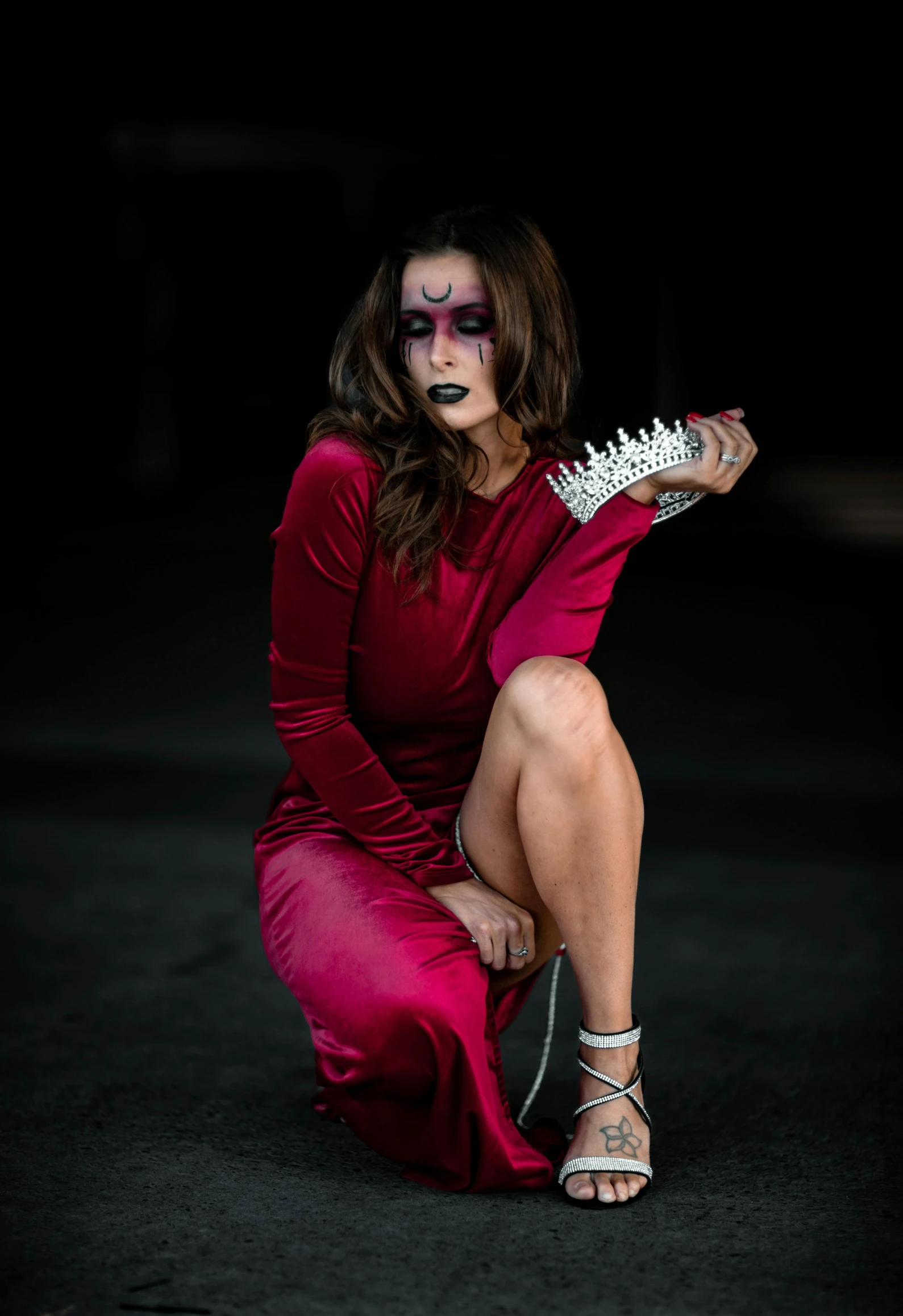 a woman with makeup sitting on a black floor