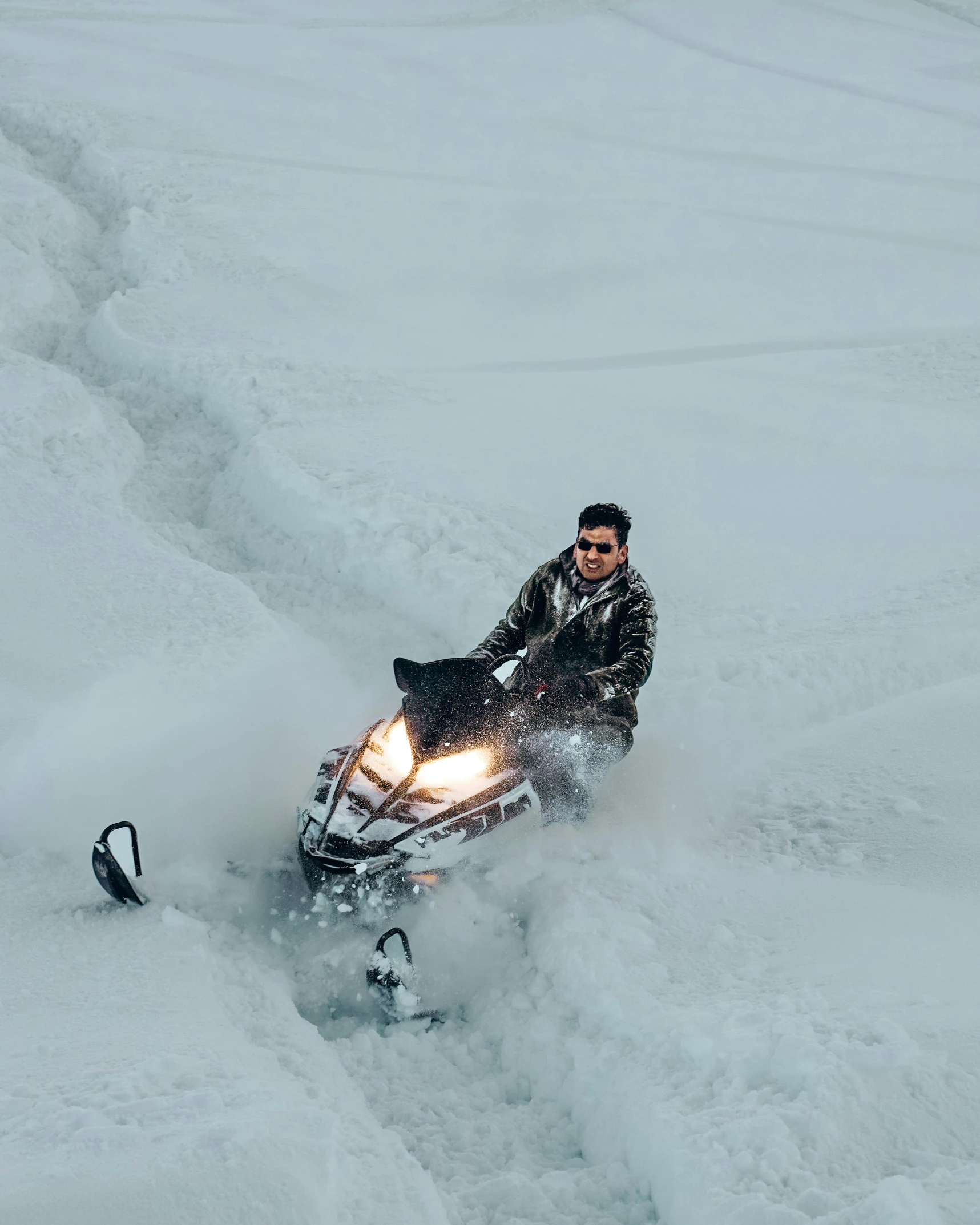 a man riding a snowmobile down the middle of a snowy hill