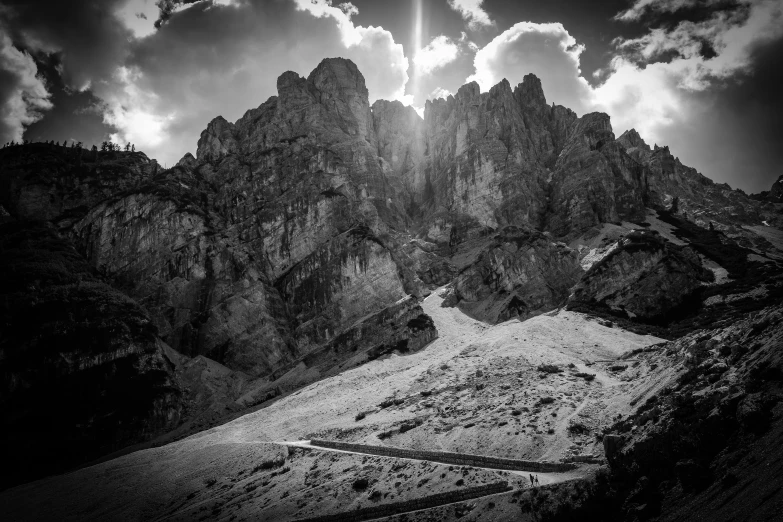 an image of a mountain setting with sun peeking through clouds