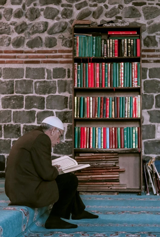 an old man sitting on the ground reading a book