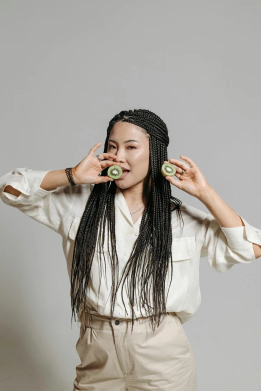 a woman in white shirt with two halves of cucumber