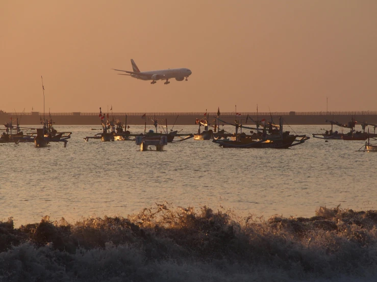 large commercial airplane landing over boats in water