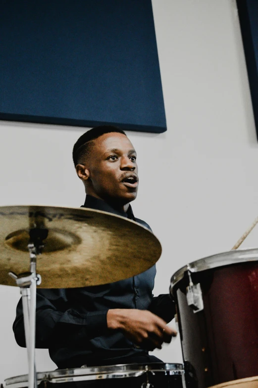 a drummer in a black suit plays with red drums