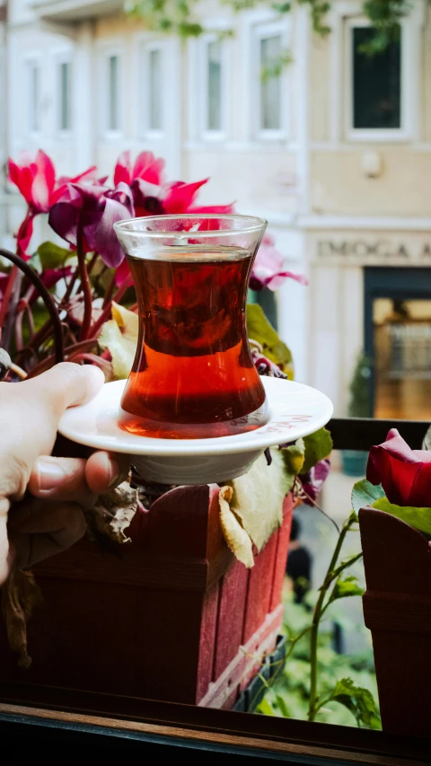 the person is holding the plate with tea in it