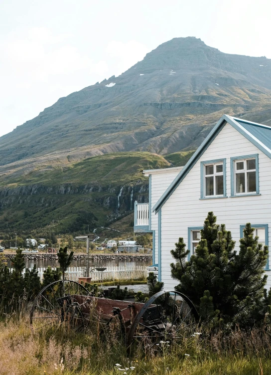 a white house near some trees and a mountain