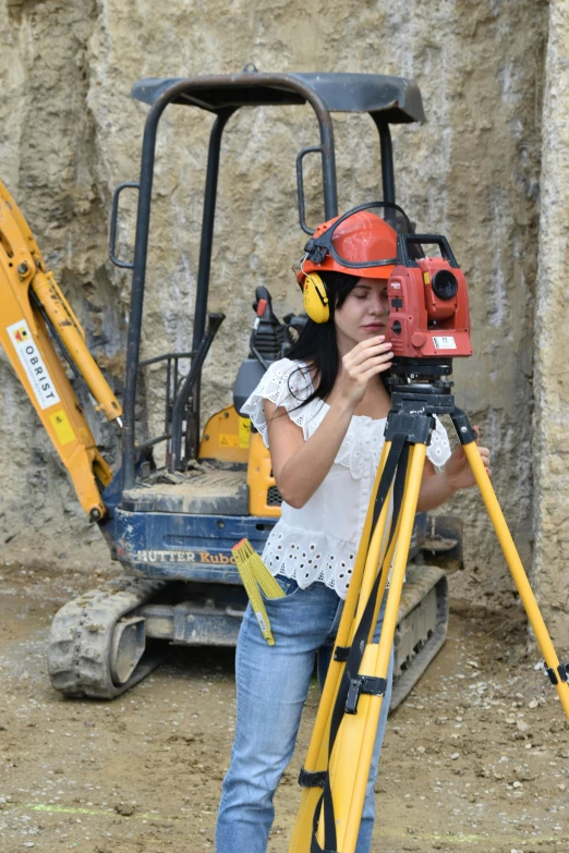 a woman in a hard hat is standing next to a camera on a tripod