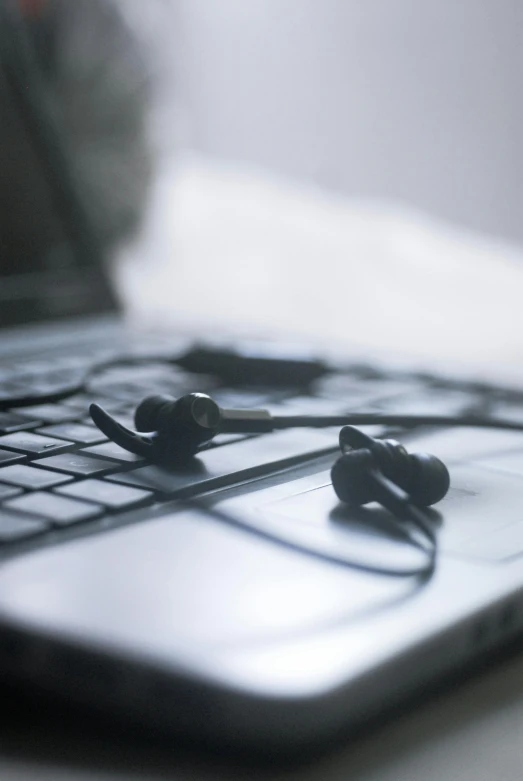 there is an open lap top computer and some ear buds laying on it