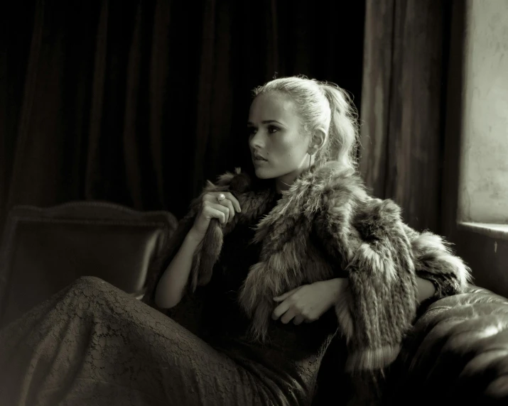 a woman is sitting on a chair wearing a fur coat