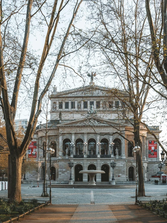 the large building is located near trees and benches