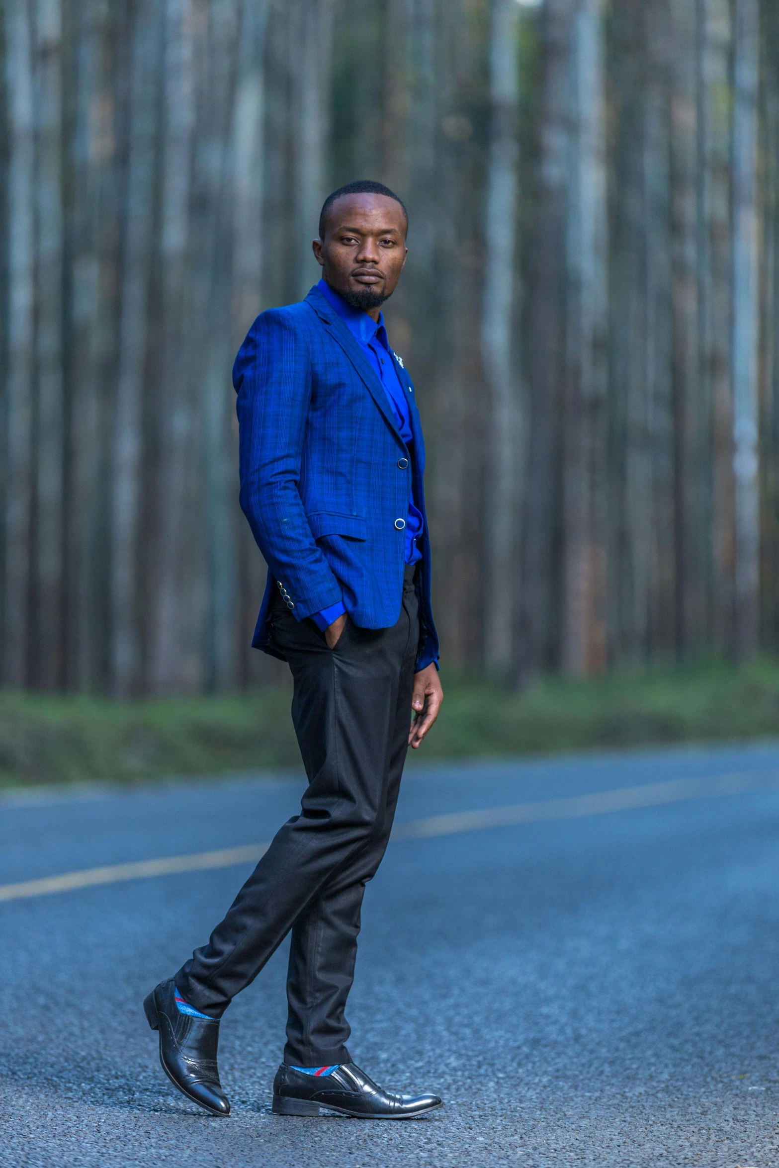 a man in blue jacket and black pants standing on the street