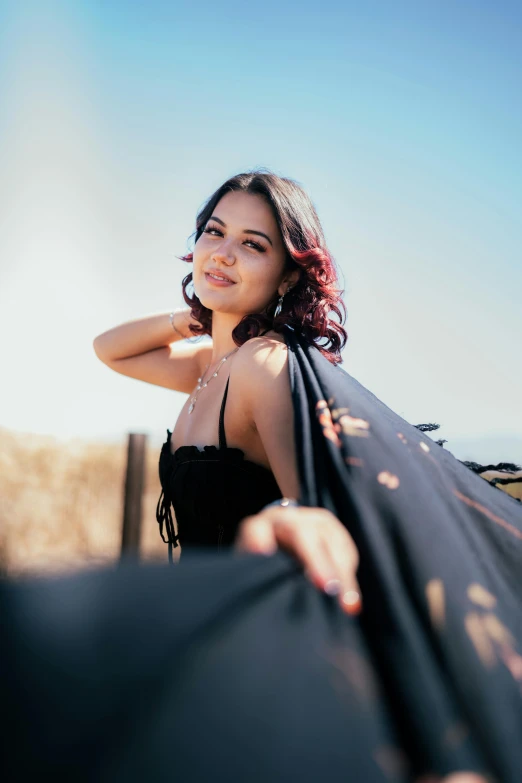 a woman poses in the wind near the roof of her car