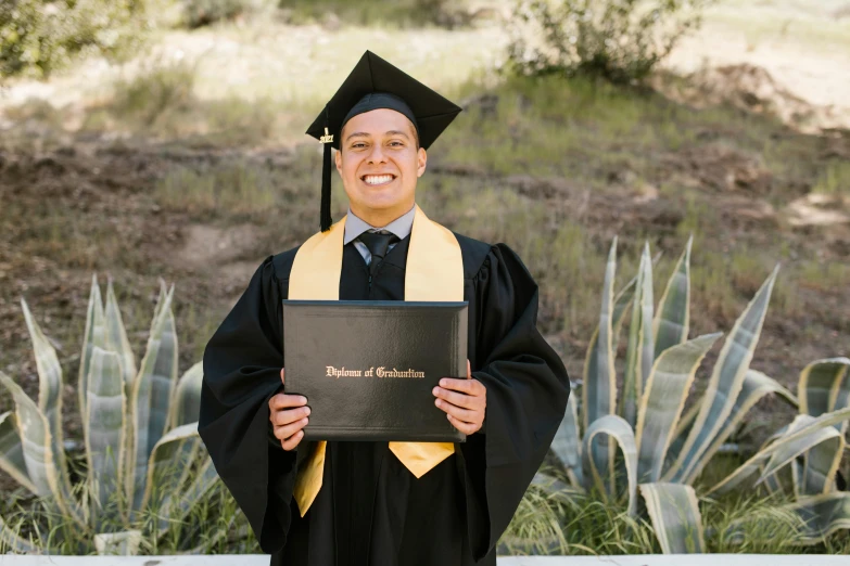 a man in a graduation gown poses for a po