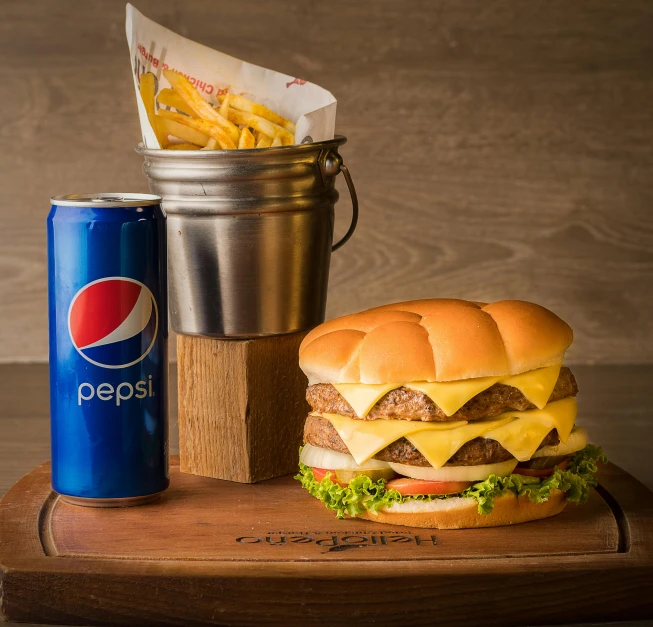 a large hamburger next to a can of pepsi