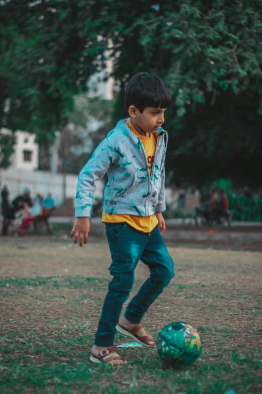 a small boy playing soccer on some grass